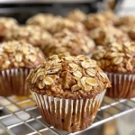 ['Close-up of a freshly baked Apple Oatmeal Muffin with a crunchy top and visible apple chunks.', 'Side view of a golden-brown Apple Oatmeal Muffin showcasing its crisp topping and moist interior.', 'Delicious Apple Oatmeal Muffin displayed with a focus on its crunchy surface and rich texture.', 'Juicy Apple Oatmeal Muffin highlighting the combination of oats and apple pieces.']