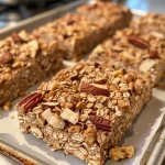 ['Close-up of homemade Apple Cinnamon Granola Bars showcasing a chewy texture with visible apple pieces and nuts.', 'Side view image of freshly made granola bars featuring chunks of dried apples and a sprinkle of cinnamon.', 'Detailed shot of granola bars with a golden-brown color, highlighting the nuts and oats mixed in.', 'Mouth-watering Apple Cinnamon Granola Bars arranged neatly, emphasizing their crunchy exterior and healthy ingredients.']