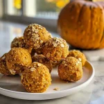 ['Close-up view of healthy pumpkin protein balls, showcasing their rich texture and color.', 'Side view of delicious no-bake pumpkin protein balls with a sprinkle of chocolate chips.', 'Juicy and textured pumpkin protein balls displayed against a simple background.', 'Detailed image of pumpkin protein balls highlighting a blend of oats and spices.']