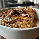 ['Close-up view of baked pumpkin oats topped with chocolate chips.', 'Side view of delicious pumpkin baked oats in a bowl.', 'Rich and creamy pumpkin baked oats ready to eat.', 'A serving of pumpkin baked oats garnished with oats and chocolate chips.']