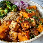 ['A close-up view of a Roasted Butternut Squash Quinoa Bowl featuring vibrant ingredients.', 'Side view of a colorful nourish bowl with roasted butternut squash, quinoa, and fresh vegetables.', 'Juicy and delicious Roasted Butternut Squash Quinoa Bowl with tofu and broccoli, captured beautifully.', 'A close-up shot highlighting the textures of a roasted butternut squash and quinoa dish with garnishes.']
