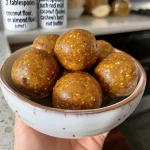 ['Close-up of healthy pumpkin pie energy balls on a wooden board.', 'Side view of energy balls resembling pumpkin pie with spices scattered around.', 'A cluster of no-bake pumpkin pie energy balls, showcasing texture and ingredients.', 'Juicy, healthy energy balls made from pumpkin and nuts, captured in natural light.']