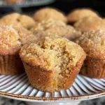 Close-up view of golden-brown apple cider donut muffins with a dusting of cinnamon sugar.