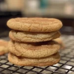 A close-up side view of freshly baked snickerdoodle cookies with a golden-brown exterior.