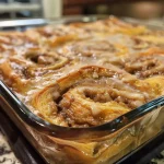Close-up view of a sliced cinnamon roll casserole topped with creamy frosting.